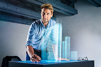 Ein Mann interagiert bearbeitet ein holografisches 3D-Gebäude.